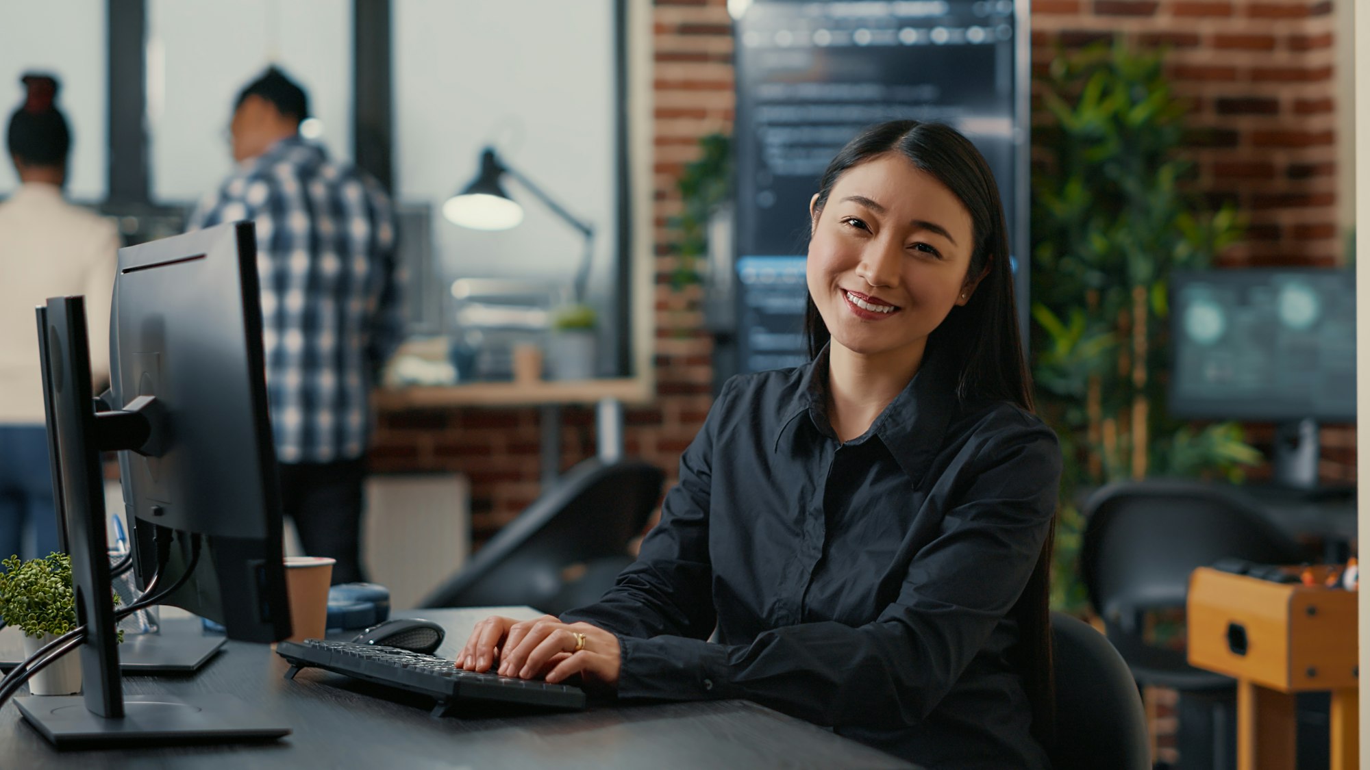 Smiling asian database software developer writing programming code on computer keyboard